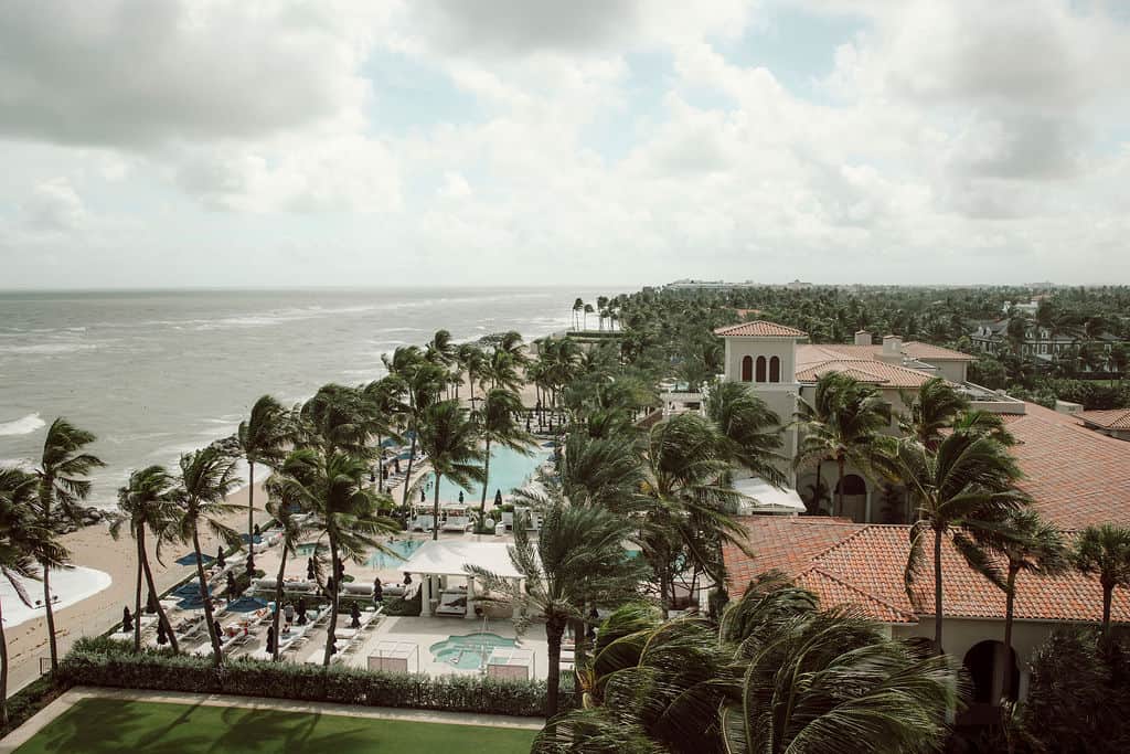 Scenic view of a beachfront resort with palm trees and ocean in the background.