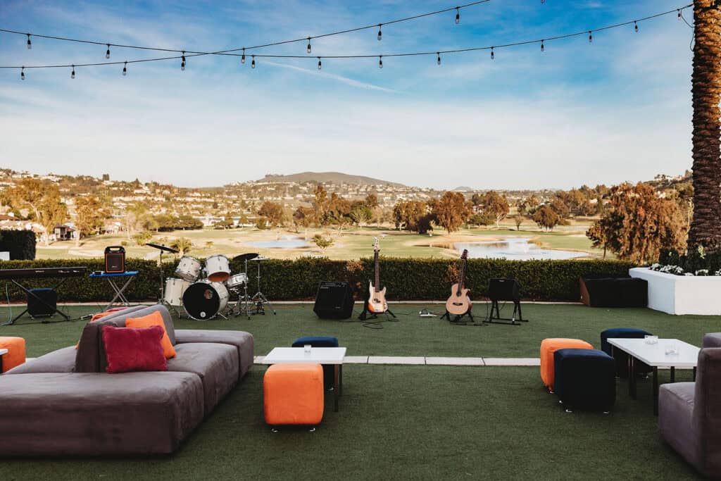 Outdoor event space with musical instruments and seating under string lights.