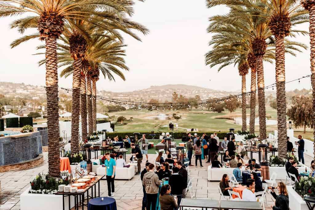 Outdoor event at Blank Space Events with palm trees and guests enjoying a gathering.
