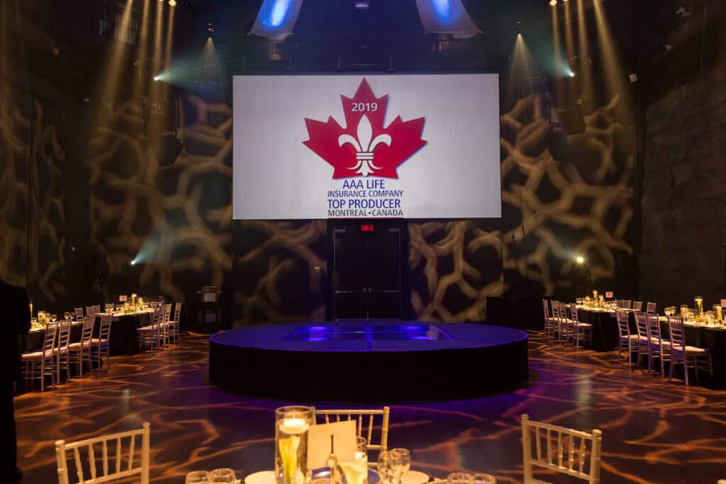 Event stage with large screen displaying 2019 AAA Life Insurance awards in Montreal.