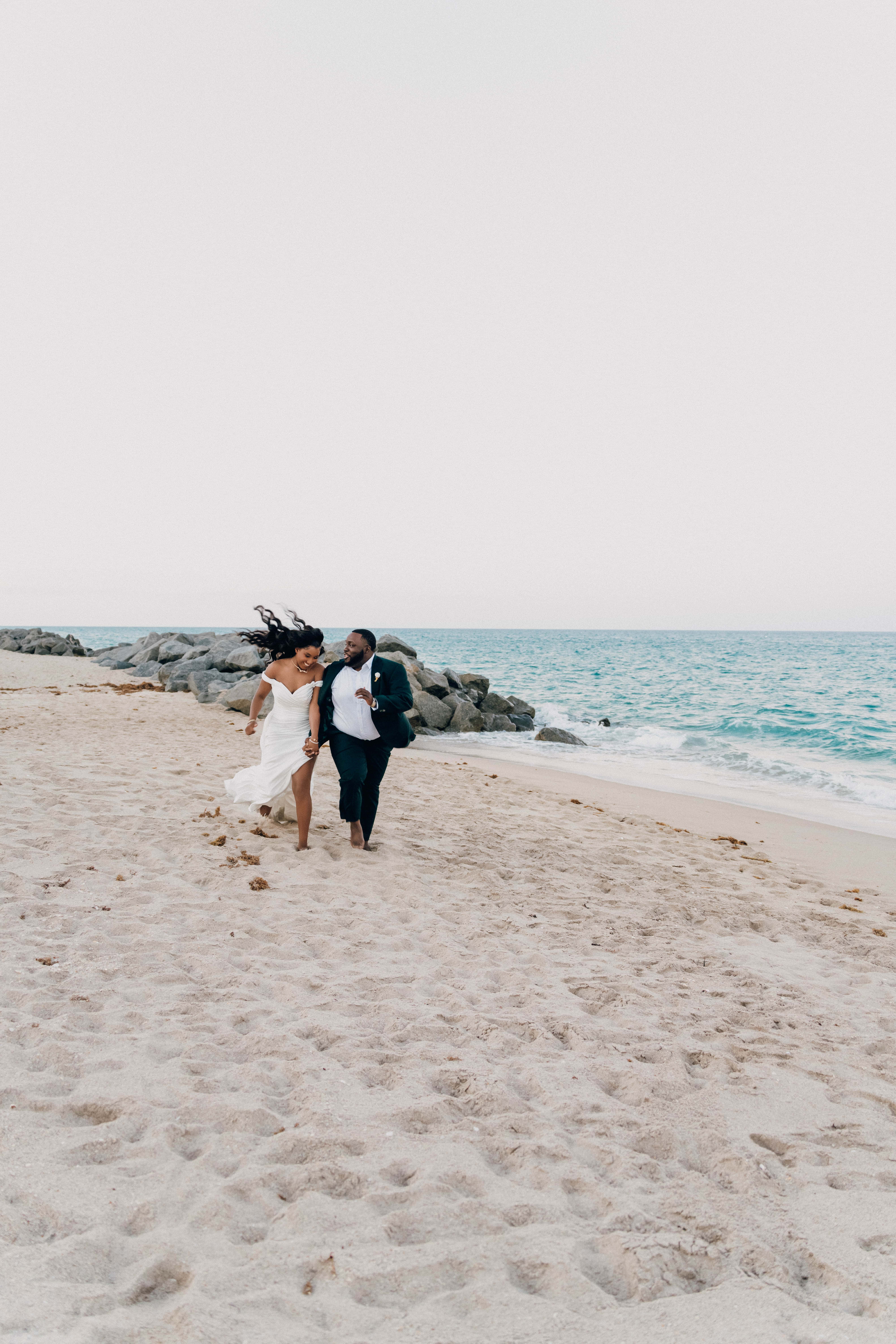 Bride and groom walking on the beach during a wedding ceremony.