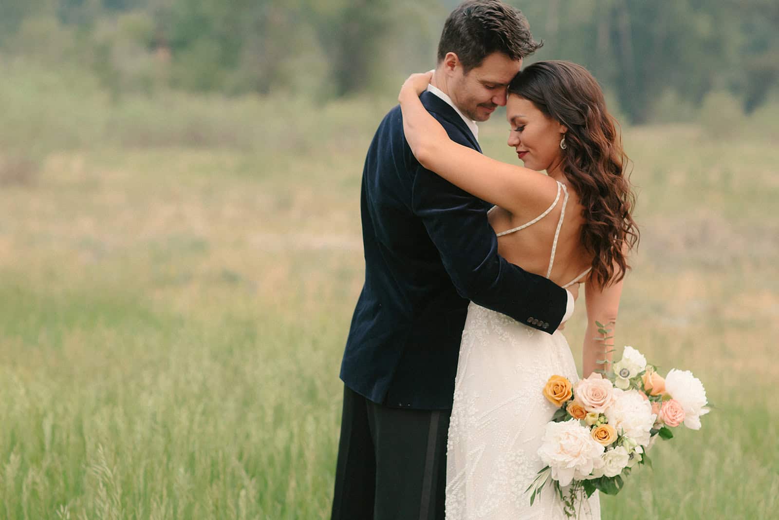 Elegant bride and groom embracing outdoors during wedding ceremony.