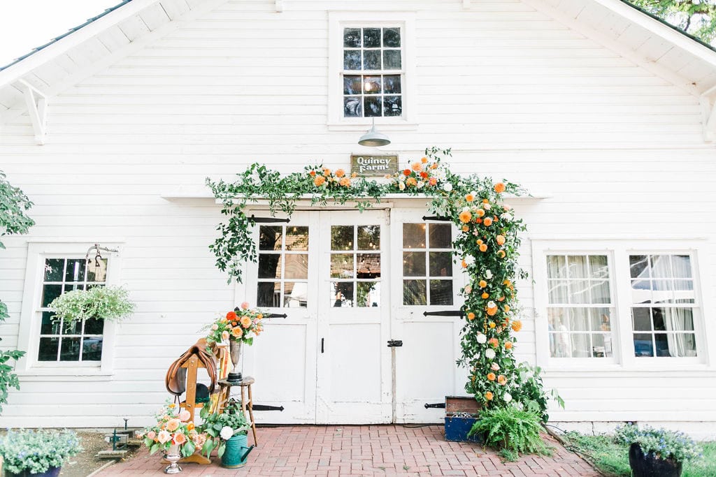 Elegant wedding venue decorated with orange and green floral arch at Elizabeth & Kelly's celebration.