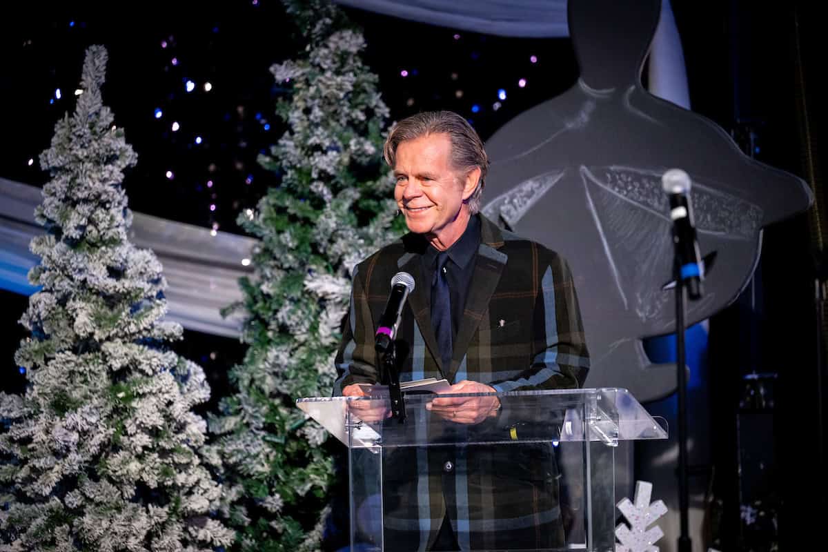 Man speaking at a show production event with Christmas trees and decorations.