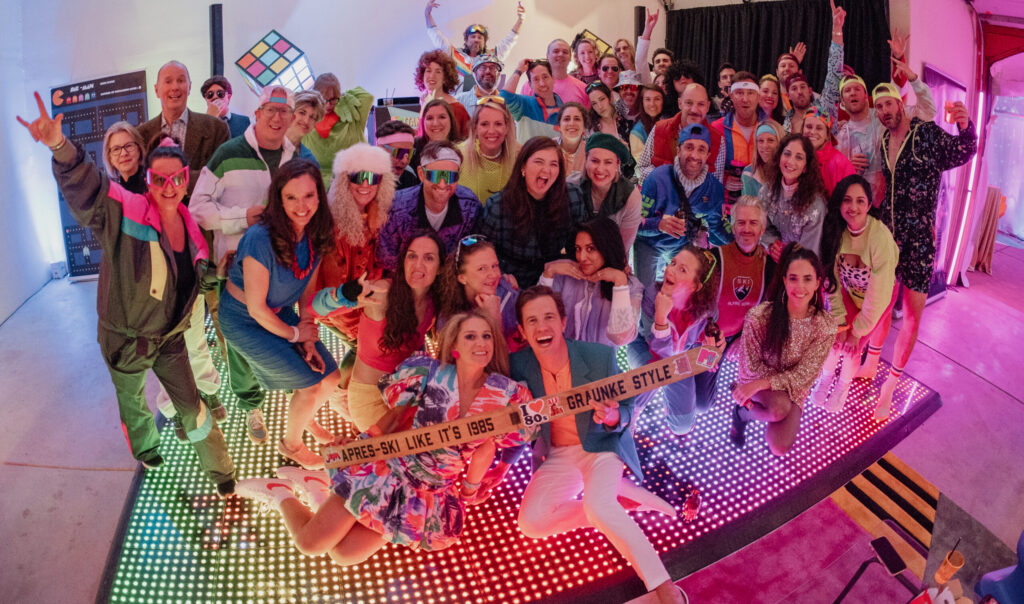 Group of people celebrating at a themed event with colorful lighting and decorations.