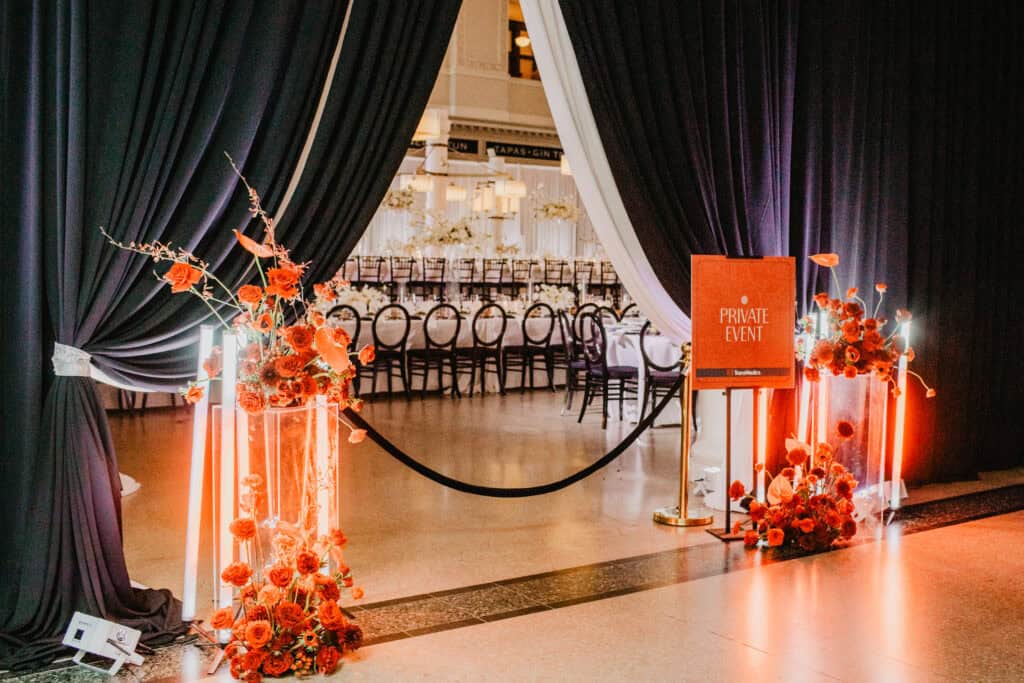 Elegant private event entrance with floral arrangements and draped curtains.