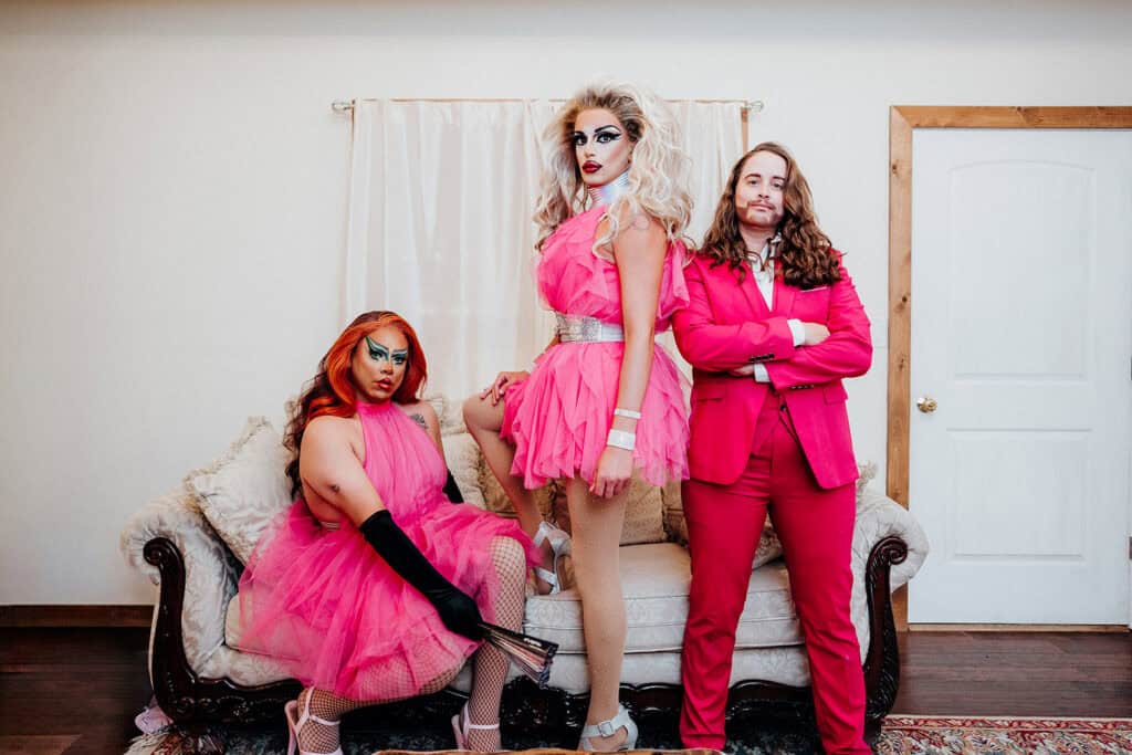 Drag performers in vibrant pink costumes at a social event.