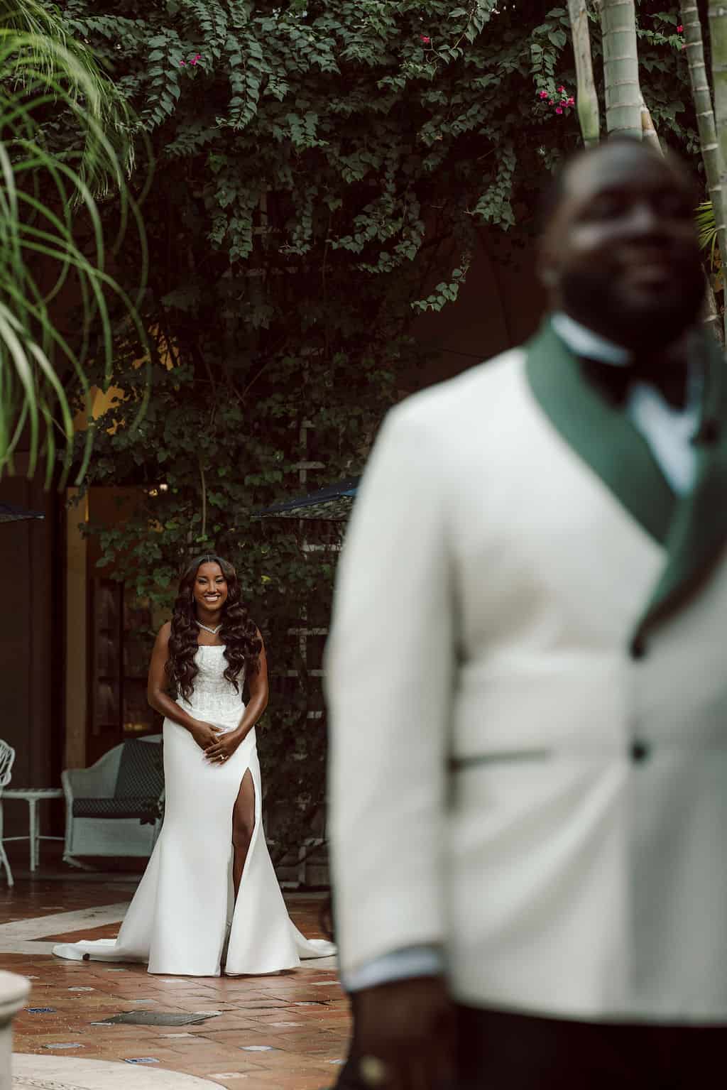 Elegant bride in white gown with groom in tuxedo at outdoor wedding venue.