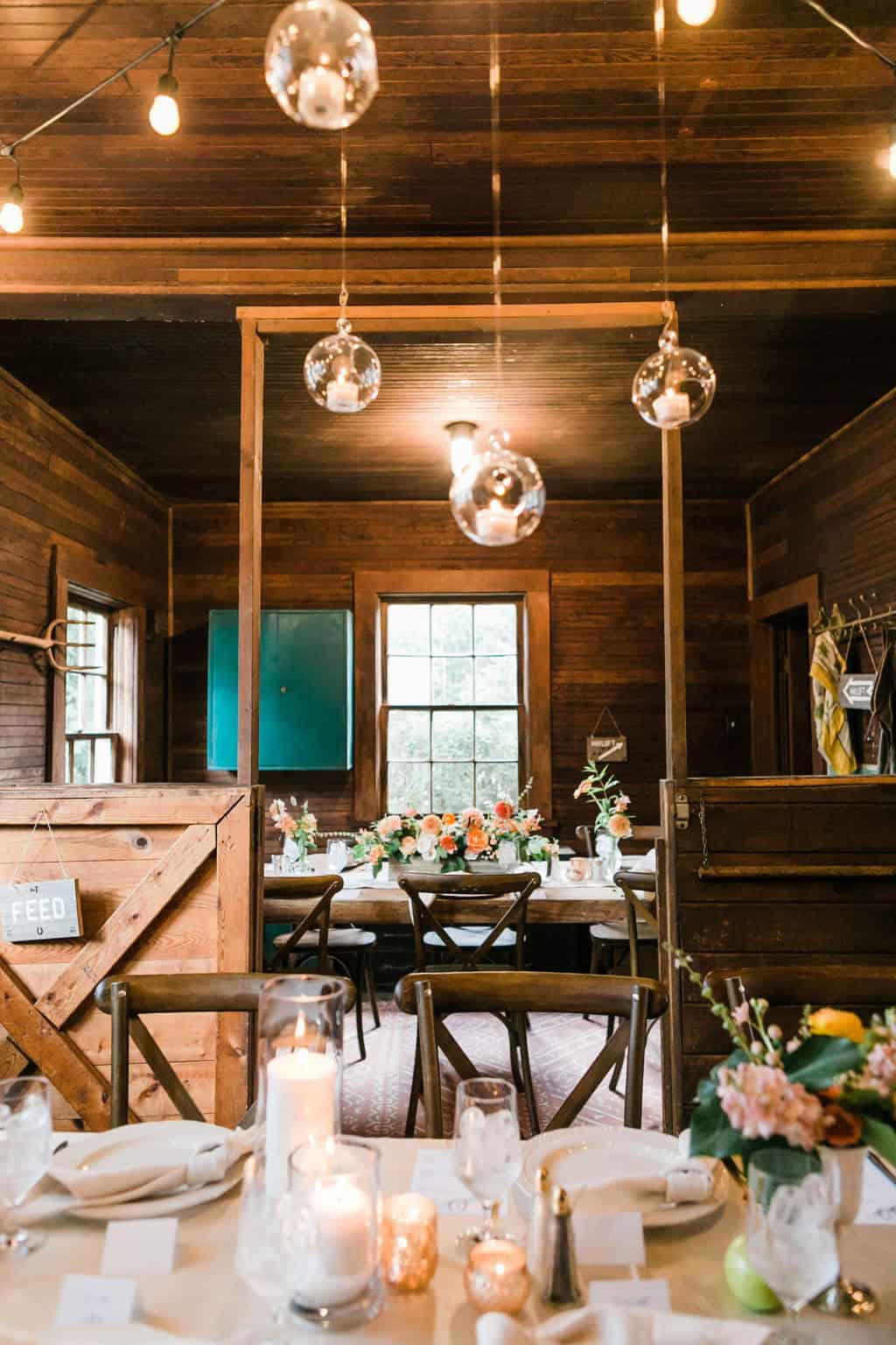Elegant rustic wedding reception with hanging glass globes and floral centerpieces.