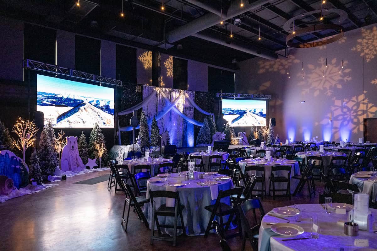 Elegant winter-themed event setup with snowflake decorations and large screens.